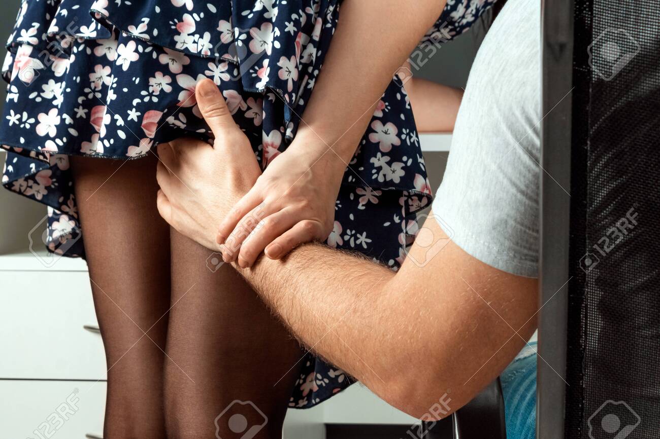 A male hand climbs a girl under a skirt. Touch the ass and leg of an office girl. He is sexually abusing. Women are sexually abused. Sexual abuse concept, victim.